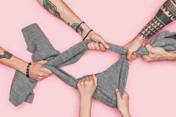 cropped view of shopaholics pulling grey scarf isolated on pink - Foto, immagini