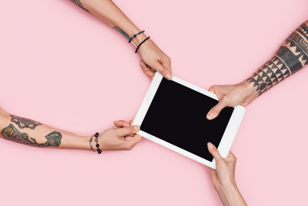 osittainen näkymä shopaholics vetämällä digitaalinen tabletti tyhjä näyttö eristetty vaaleanpunainen
 - Valokuva, kuva