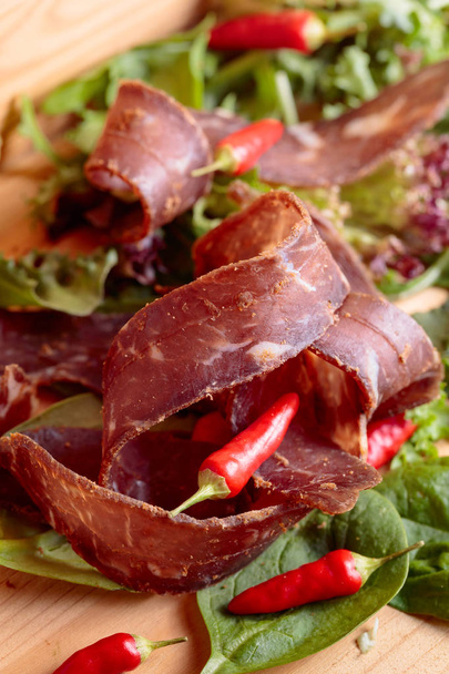Healthy dry beef jerky with herbs and small red peppers. - Photo, Image