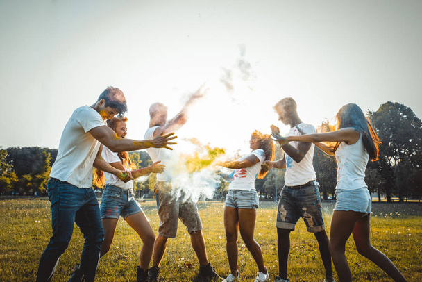 Група щасливих друзів, які грають з кольорами холі в парку - молоді дорослі розважаються на фестивалі холі, концепції про веселощі, веселощі та молоде покоління
 - Фото, зображення