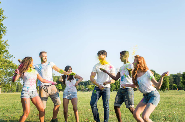 Grupo de amigos felizes brincando com cores holi em um parque - Jovens adultos se divertindo em um festival holi, conceitos sobre diversão, diversão e geração jovem
 - Foto, Imagem