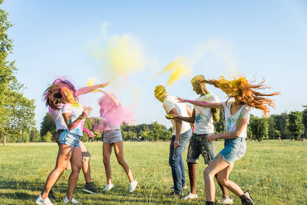 Group of happy friends playing with holi colors in a park - Young adults having fun at a holi festival, concepts about fun, fun and young generation - 写真・画像