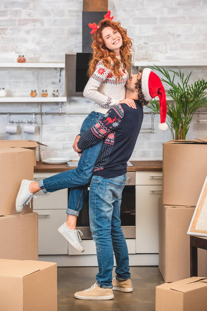 heureux jeune couple câlin tout en déménageant dans nouvelle maison à christmastime
   - Photo, image