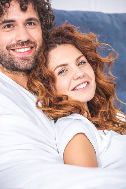 close-up view of happy young couple embracing in bed - Foto, Bild