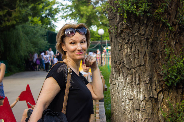 Blonďatá žena 40 let v parku v černý top - Fotografie, Obrázek