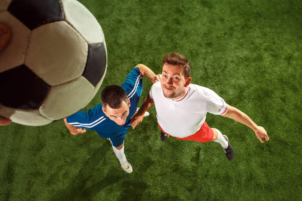 Football players tackling for the ball over green grass background - Foto, imagen