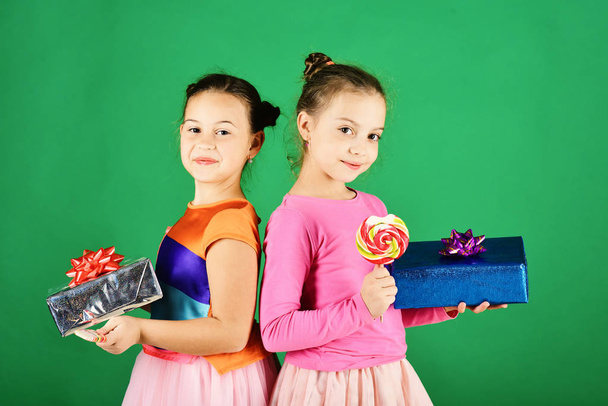 Sisters with lollipops, boxes and bags. Children eat colorful caramels - Foto, imagen