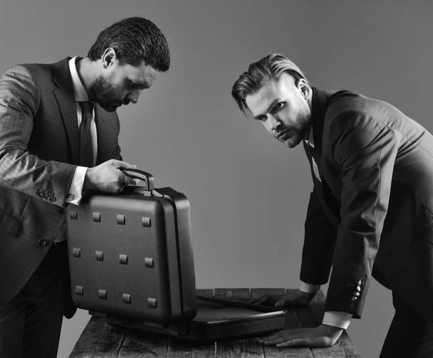Businessmen look into opened briefcase on dark background. - Foto, immagini