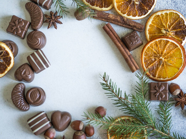 Christmas or New Year's frame of chocolate sweets, spices, orange dry slices and fir branches. Top view. Copy space - Foto, imagen