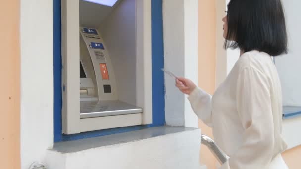 jonge vrouw invoegen van een credit card naar ATM-, de bancaire sector, de zakelijke vrouw mooi meisje na werk in de bank, winkelcentrum - Video