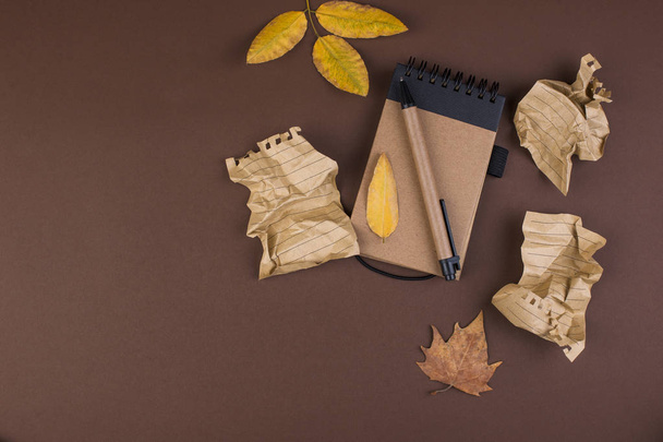 Notepad and crumpled sheets for writing, difficult work to write a letter. Free space for text. Autumn atmosphere and yellow leaves. Top view. Copy space - Foto, afbeelding