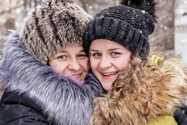 Mam en dochter zijn gelukkig samen. Portret van moeder en dochter in de straat in de winter - Foto, afbeelding