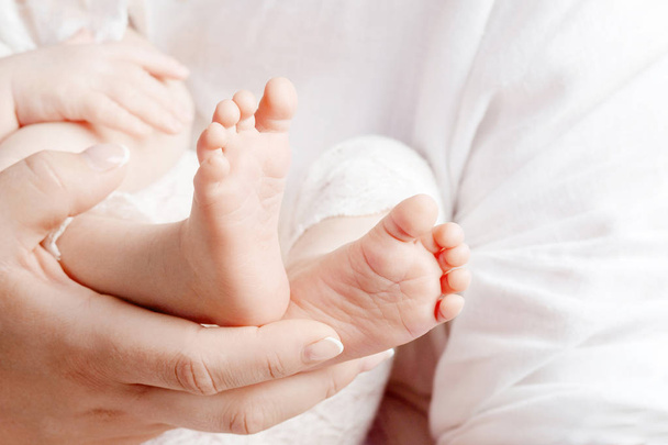Baby feet in mother hands. Tiny newborn baby's feet on female hands closeup. Mom and her child. Happy Family concept. Beautiful conceptual image of parenthood - Foto, afbeelding