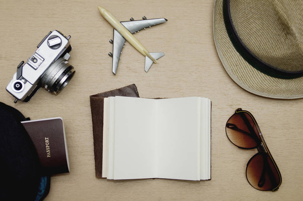 Flaches Blanko-Notizbuch auf Holztisch mit Reiseutensilien, Urlaubskonzept - Foto, Bild