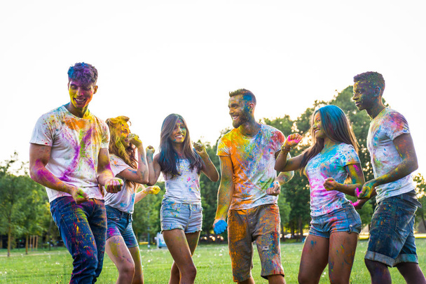 Group of happy friends playing with holi colors in a park - Young adults having fun at a holi festival, concepts about fun, fun and young generation - Foto, Bild