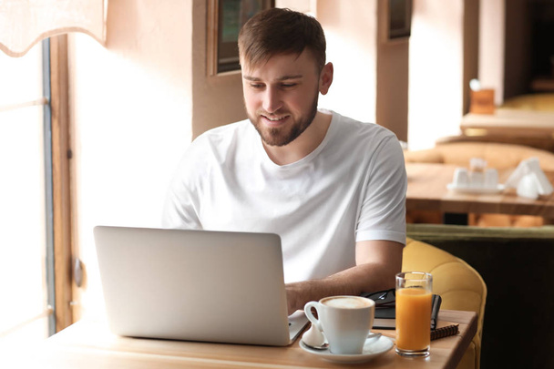 Young freelancer with laptop working in cafe - Photo, image