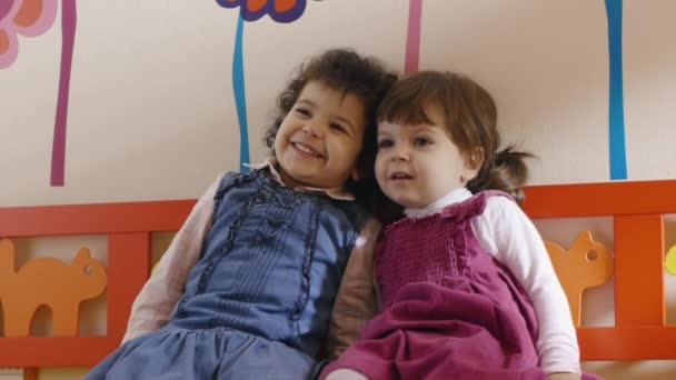 Jardín de infancia: amiguitas sentadas en el banco de la escuela, jugando y sonriendo
 - Imágenes, Vídeo