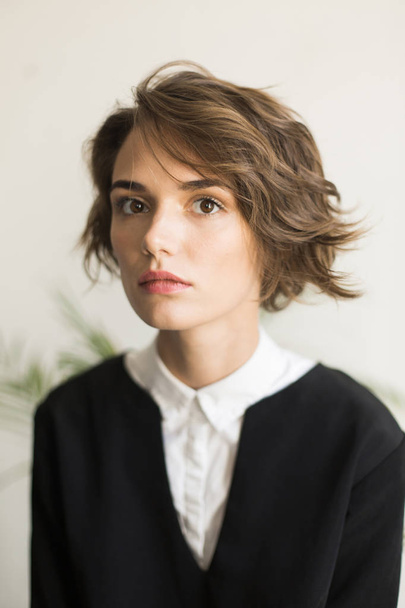 Portrait of young beautiful woman with short curly hair thoughtfully looking in camera isolated - Foto, afbeelding