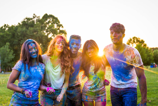 Group of happy friends playing with holi colors in a park - Young adults having fun at a holi festival, concepts about fun, fun and young generation - Foto, Imagem