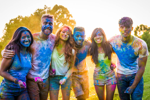 Group of happy friends playing with holi colors in a park - Young adults having fun at a holi festival, concepts about fun, fun and young generation - Photo, Image