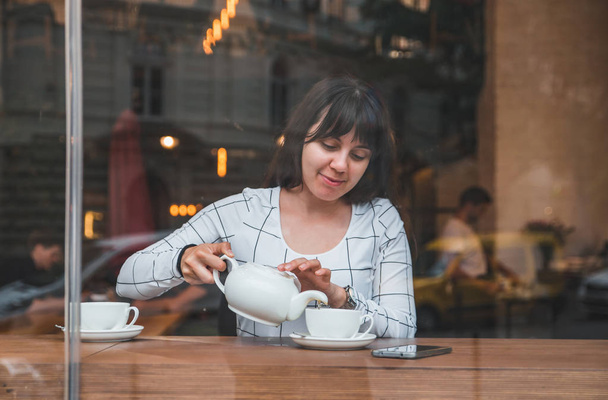 tea csészében kávézó ömlött nő. Nézd át üveg ablak - Fotó, kép