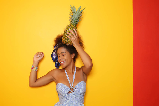 Krásná afroamerická žena s ananasem na barevném pozadí - Fotografie, Obrázek