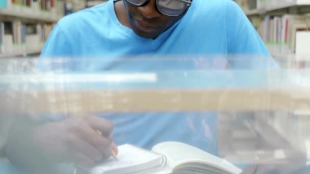 Student sitzt in Bibliothek, liest Buch und macht sich Notizen. - Filmmaterial, Video
