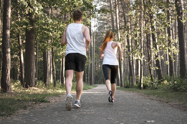 Sporty coppia bianca jogging nella foresta in estate, vista da dietro
. - Foto, immagini