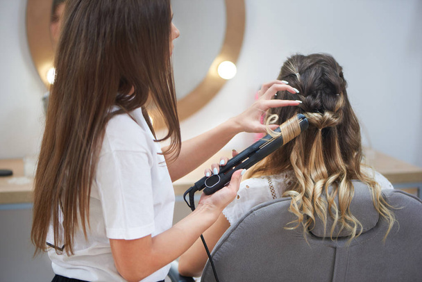 Process of making trendy hairstyle in beauty salon - Fotó, kép