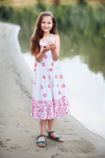 meisje speelt met een toy zeilschip door de rivier - Foto, afbeelding