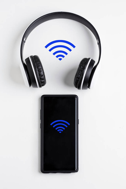 Bluetooth sluchátka poslouchat hudbu z mobilního telefonu bez kabelu na bílém pozadí - Fotografie, Obrázek