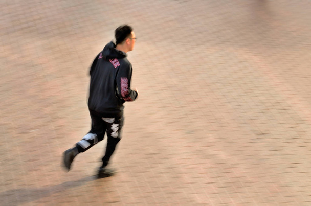 The man is dressed in a sports uniform.Jogging on the city street. - 写真・画像