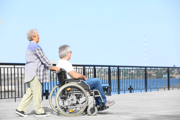 車椅子と彼の妻を屋外で年配の男性 - 写真・画像