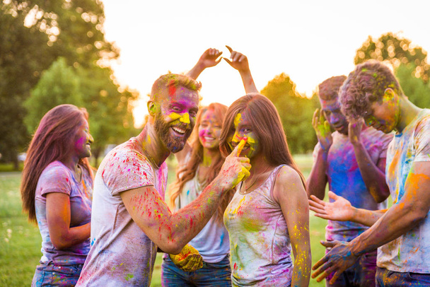 Group of happy friends playing with holi colors in a park - Young adults having fun at a holi festival, concepts about fun, fun and young generation - Photo, image