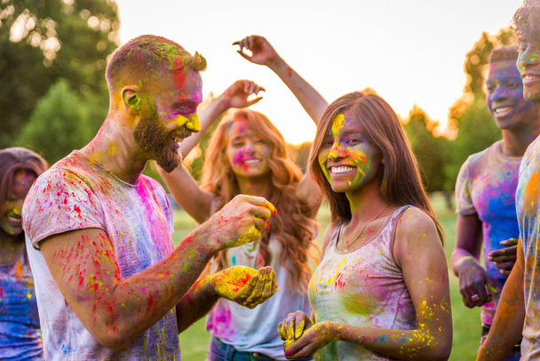 Group of happy friends playing with holi colors in a park - Young adults having fun at a holi festival, concepts about fun, fun and young generation - Zdjęcie, obraz