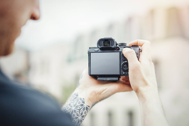 Close up of man hands holding camera and making photos of modern building. - Photo, image