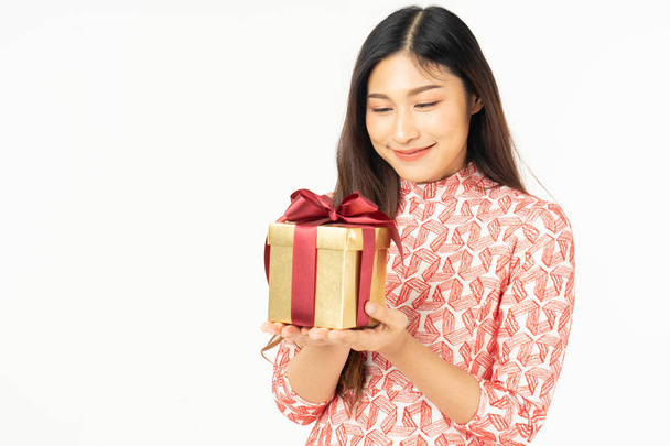 Photo of asian curious woman in red dress rejoicing her birthday or new year gift box. Young woman holding gift  box with red bow being excited and surprised  holiday present isolated white background - Fotografie, Obrázek