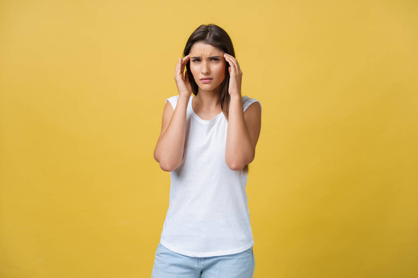 Die junge Frau leidet unter Kopfschmerzen vor gelbem Hintergrund. Studioaufnahme - Foto, Bild