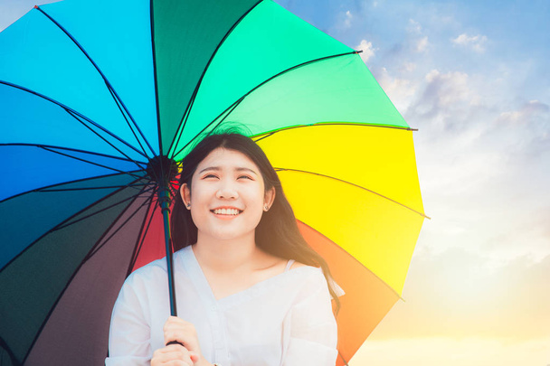 Söpö aasialainen teini onnellinen hymy ulkona sateenkaaren värikäs sateenvarjo aurinkoinen päivä
 - Valokuva, kuva