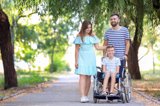 Мальчик-подросток в инвалидной коляске с семьей, гуляющей на улице
 - Фото, изображение