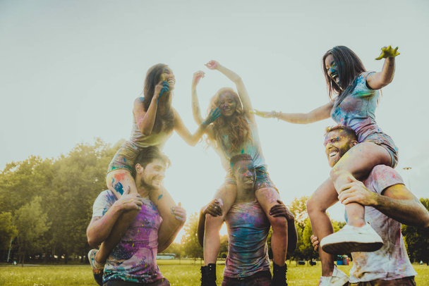 Group of happy friends playing with holi colors in a park - Young adults having fun at a holi festival, concepts about fun, fun and young generation - Foto, Imagen