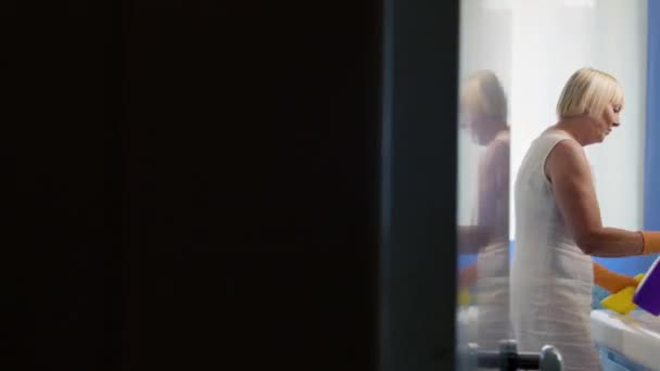 stará žena, která dělá domácí práce v koupelně doma - Záběry, video