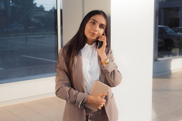 Young attractive girl in business suit uses smartphone. Lifestyle and business portrait - Foto, Imagen