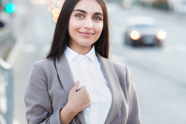 Young attractive girl in business suit on background of road. Lifestyle and business portrait - Photo, Image