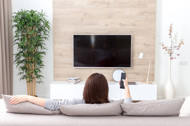 jonge vrouw kijken tv in de kamer - Foto, afbeelding