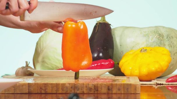 Female hands are cut with a knife orange bell pepper. mixture of vegetables for cooking vegetable stew. background color. the concept of healthy eating and harvesting. - Foto, afbeelding