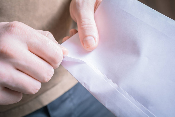 Mãos masculinas abrindo a borda de um envelope - esperando por um conceito de mensagem
 - Foto, Imagem