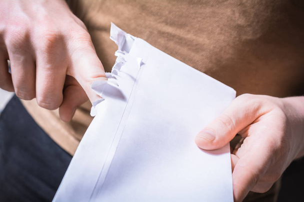 Мужские руки разрывают край конверта - нетерпеливый ожидая концепции послания
 - Фото, изображение