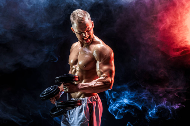 Topless man exercising biceps with dumbbells in studio - Foto, imagen