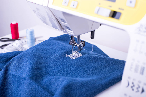 Jeans Fabric On Sewing Machine Under Sewn Foot Close Up. - 写真・画像
